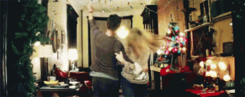 a man and a woman are dancing in front of a christmas tree in a living room .