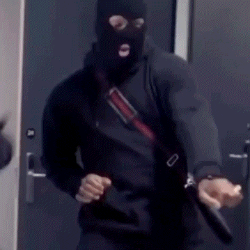 a man in a mask is holding a gun in front of a door