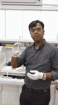a man wearing glasses and gloves holds a syringe in his hand