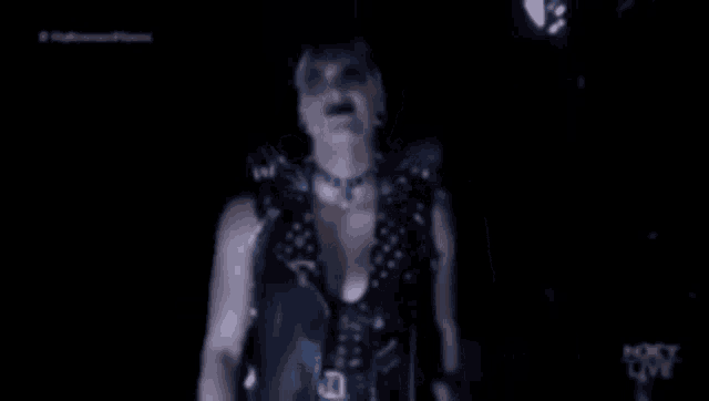 a woman in a black leather jacket is standing in the dark .