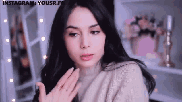 a woman wearing a sweater and a ring looks at the camera with the words instagram yousr.f on the bottom right