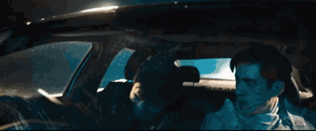 a man is sitting in a car with another man behind him