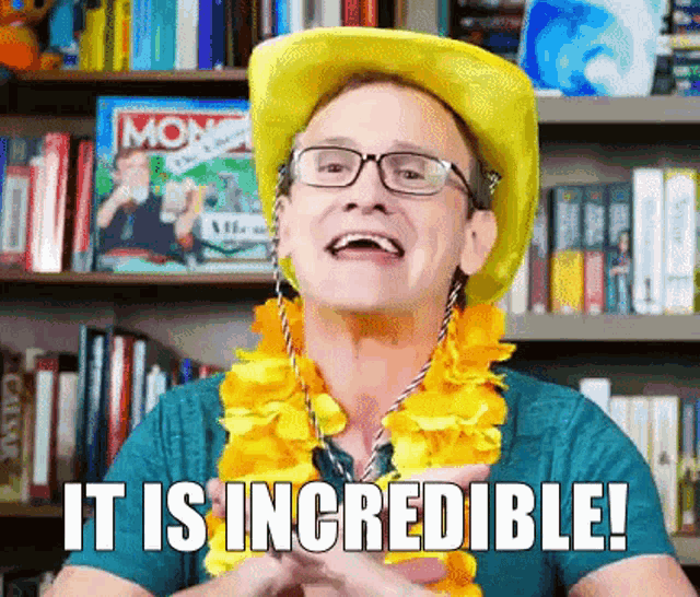a man wearing a yellow hat and glasses says it is incredible in front of a bookshelf