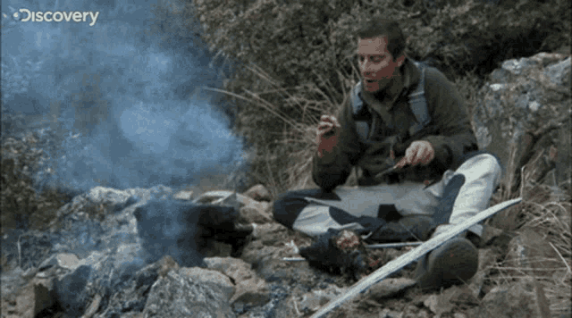 a man is sitting in front of a fire with discovery written on the bottom