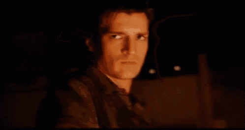 a man is holding a gun in his hand and pointing it at the camera .