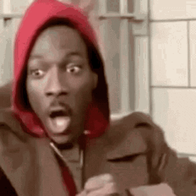 snoop dogg is wearing a red hoodie and making a funny face .
