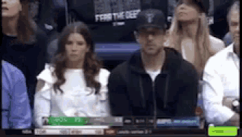 a man and a woman are sitting in a stadium watching a game .