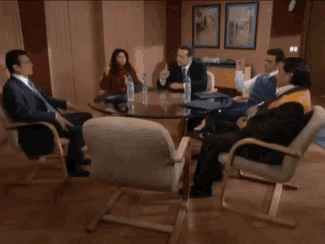 two men are sitting at a table with a bottle of aquafina water in front of them .