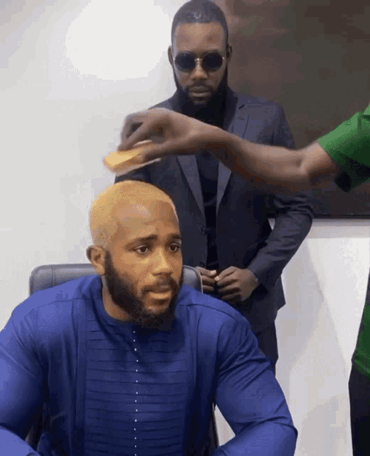 a man in a blue shirt is sitting in front of another man in a suit