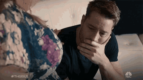 a man covering his mouth while sitting on a couch with a woman in a floral dress and the hashtag #thisisus
