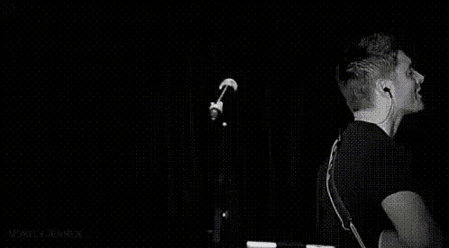 a black and white photo of a man singing into a microphone .