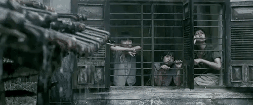 a group of children are looking out of a window with bars .
