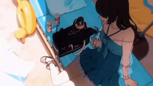 a girl in a blue dress is sitting next to a suitcase with a owl on it