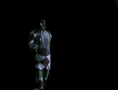 a man in a colorful outfit singing into a microphone in the dark