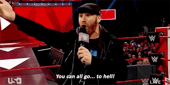 a man is standing in a wrestling ring holding a microphone and saying `` you can all go to hell '' .