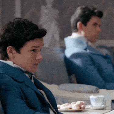 a boy in a blue suit sits next to another boy