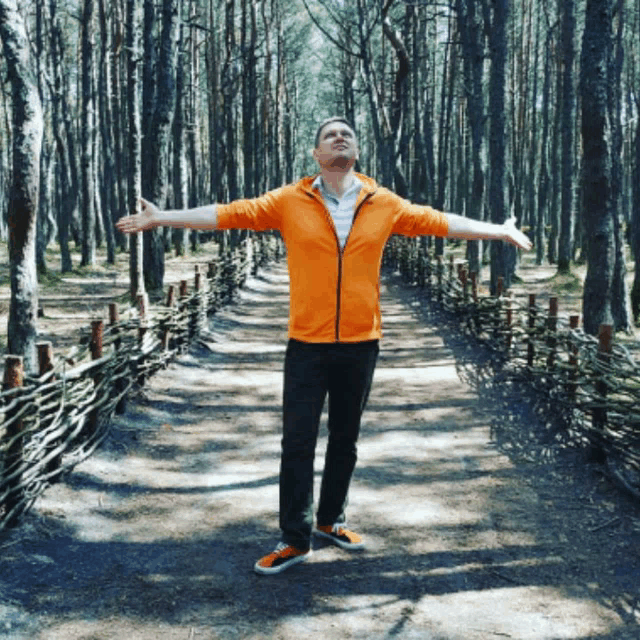 a man with his arms outstretched in a forest