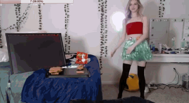 a woman is dancing in front of a laptop and a bag of reeses