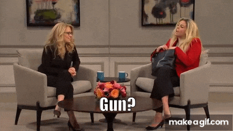 two women are sitting at a table and one of them is holding a gun