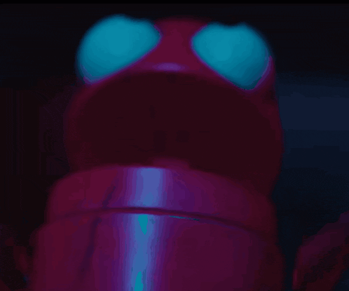 a close up of a red object with blue eyes in the dark