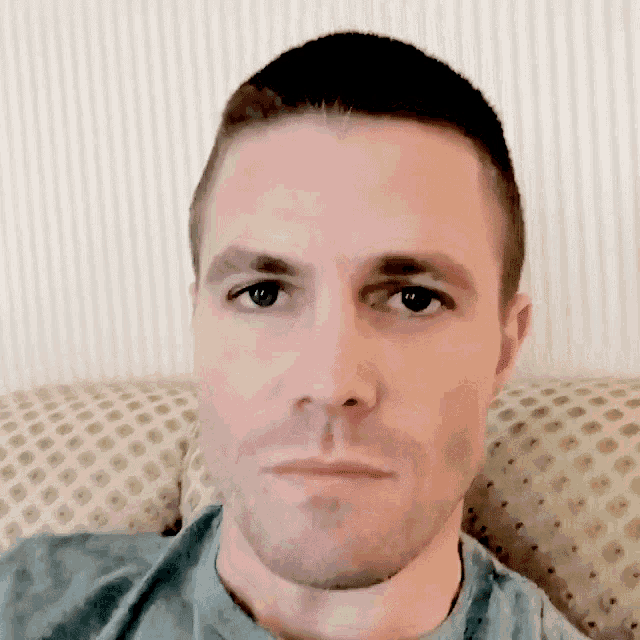 a close up of a man 's face with a striped wall in the background