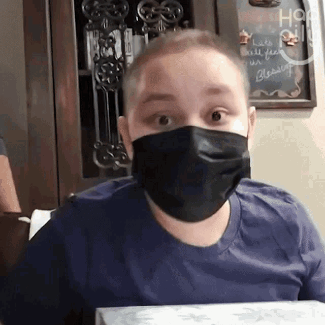 a man wearing a black face mask looks surprised at the camera