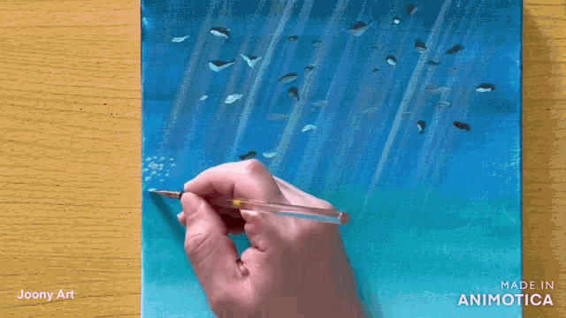 a person is painting a picture of whales in the ocean with a brush ..