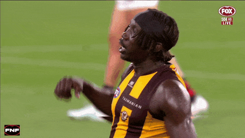 a tasmanian football player flexes his muscles in front of a fox broadcast
