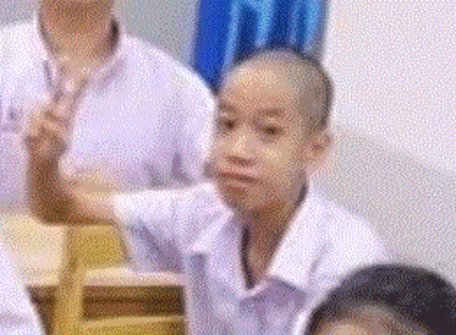 a group of children are sitting in a classroom and one of them has a shaved head .