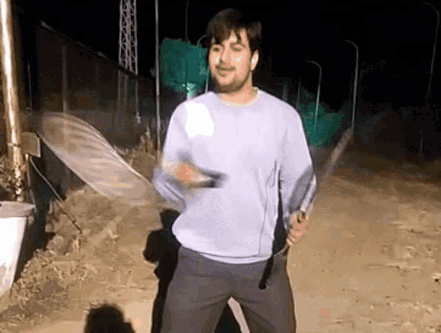 a man in a blue sweater is holding a sword