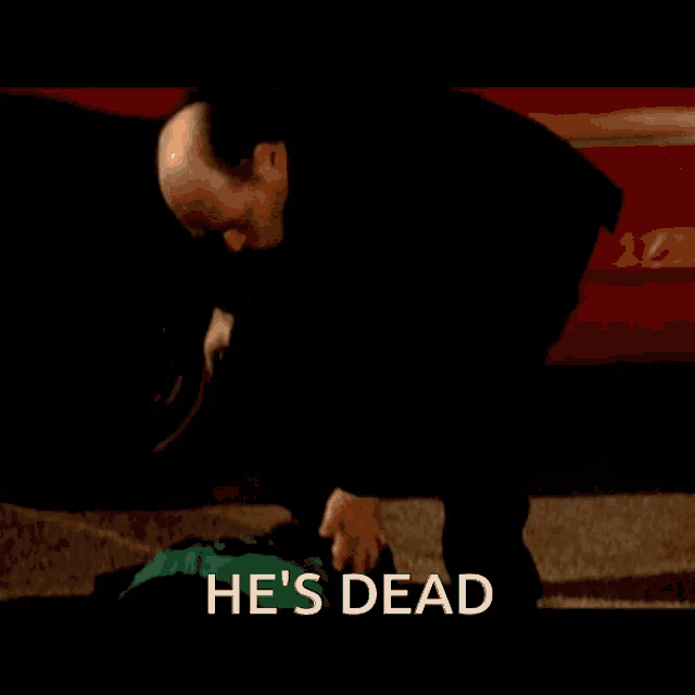 a man in a black shirt is standing next to a car with the words he 's dead below him