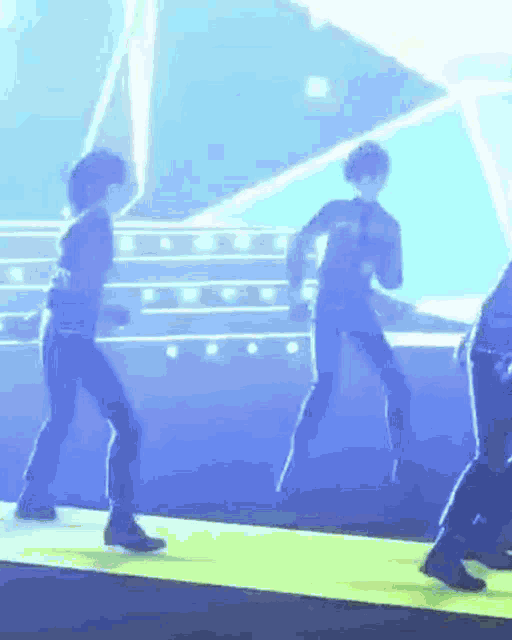 a group of people are dancing on a stage in front of a blue light .
