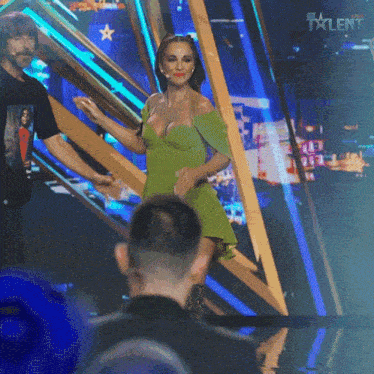 a woman in a green dress is dancing on a stage in front of a sign that says " six talent "