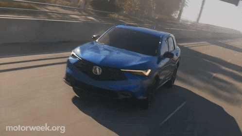 a blue car is driving on a highway with motorweek.org written on the bottom