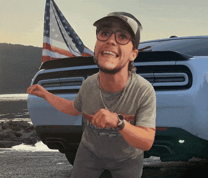 a man wearing a hat and glasses stands in front of a white car