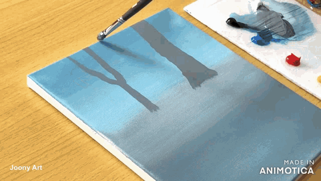 a painting of trees is being painted on a canvas by joony art
