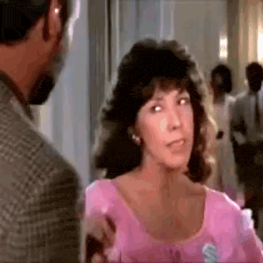 a man and a woman are standing next to each other in a hallway . the woman is wearing a pink shirt .