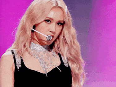 a woman with blonde hair is wearing a black top and silver necklace