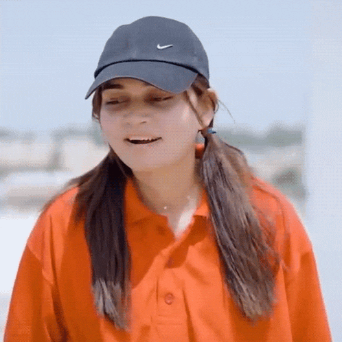 a woman wearing a nike hat and an orange shirt