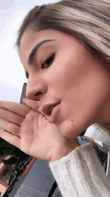 a close up of a woman holding her hand to her mouth