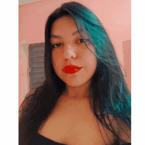 a woman with long blue hair and red lipstick looks at the camera