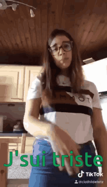 a girl wearing glasses and a shirt that says j 'suis triste