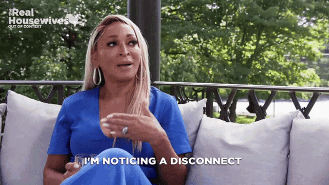 a woman is sitting on a couch with a glass of wine and says i 'm noticing a disconnect