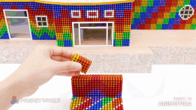 a person is holding a piece of magnets in front of a building made out of magnets