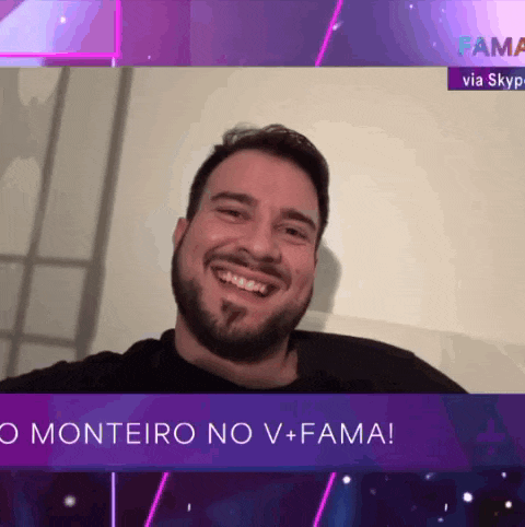 a man with a beard is smiling in front of a sign that says monteiro no v + fama