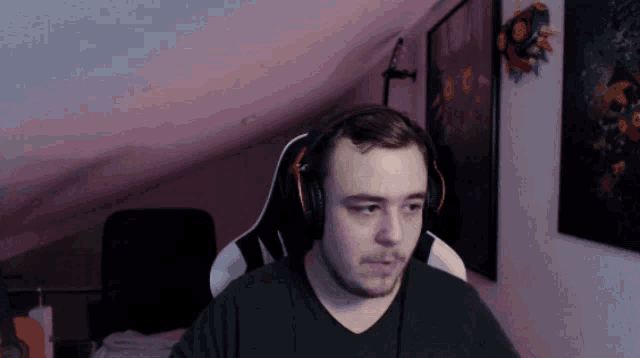 a man wearing headphones and a black shirt is sitting in a chair