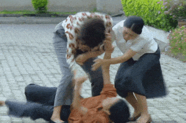 a group of people are fighting on a sidewalk
