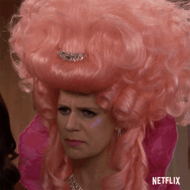 a woman in a pink wig with a netflix logo on the bottom right corner