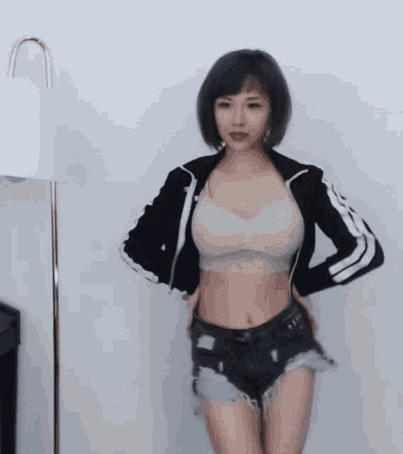 a woman wearing shorts and a crop top is dancing in front of a lamp