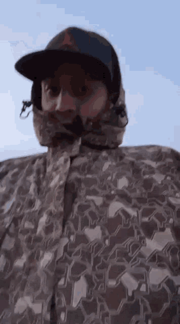 a man wearing a hat and a camouflage jacket is standing in the rain .